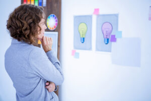 El desing thinking es una metodología en la que está trabajando una mujer mirando una pizarra para resolver problemas.